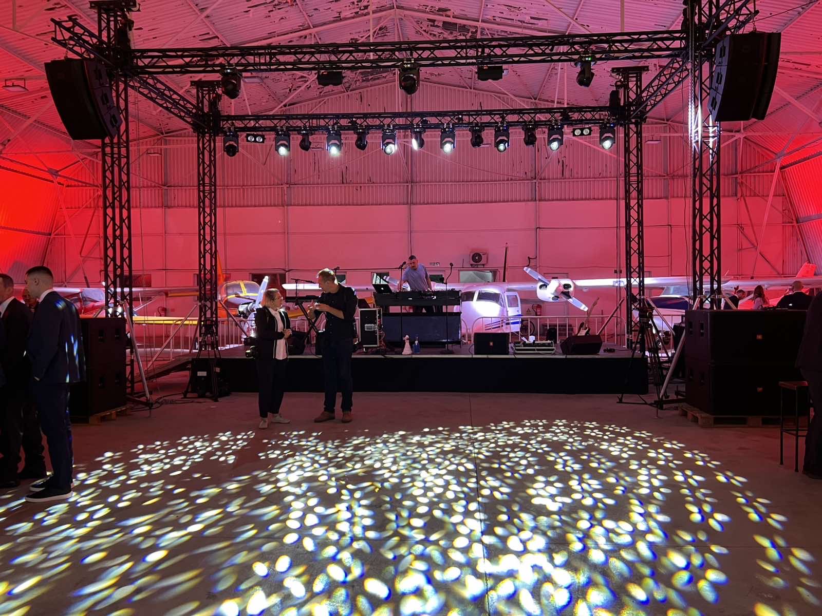 Hangar event with flown speaker arrays and DJ stage